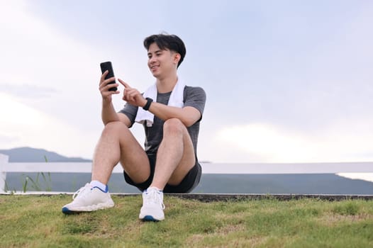 Handsome sportsman taking a break after workout and checking his mobile phone.