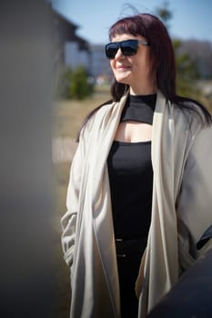 A middle-aged woman walks in suburban neighborhood, carrying a hat and sunglasses
