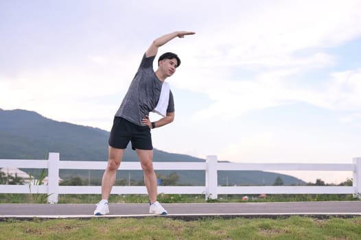 Man athlete warming up for an outdoor workout with a scenic mountain view.