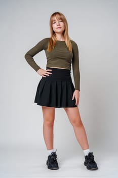 A young woman with straight hair wearing a green top poses against a neutral background in a calm setting