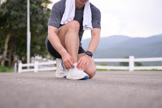 Close up active man tying shoelaces getting ready for jogging outdoors.