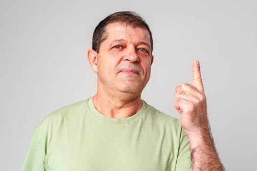 A man in a light green shirt raises his finger, signifying an important message close up