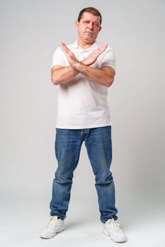 A man making a gesture of refusal with arms crossed against a light background in studio