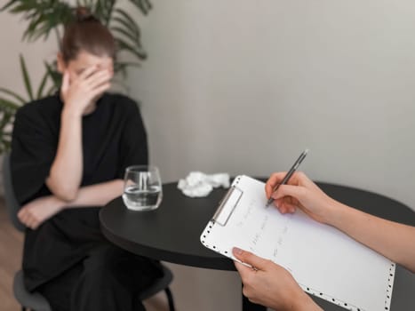 Therapy session. Woman in counseling consultation with therapist writing notes.