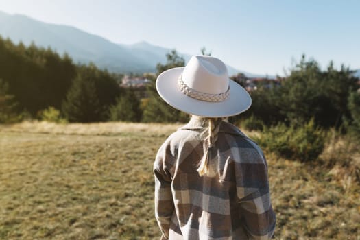 A woman stands in a meadow and looks at the mountains.