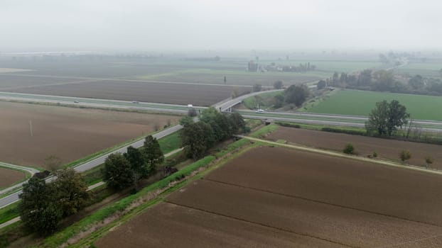 Piacenza, Italy October 15th 2024 Aerial view of a highway crossing the countryside with cars driving on a foggy day