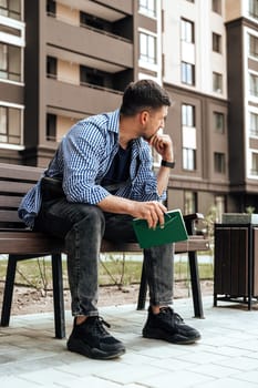 A person writes in a notebook while sitting on a park bench close up