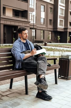 A person writes in a notebook while sitting on a park bench close up