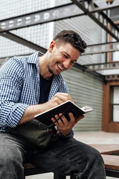 A person writes in a notebook while sitting on a park bench close up