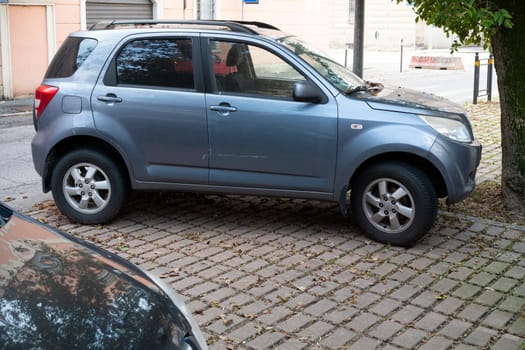 Cremona, Lombardy, Italy October 15th 2024 A grey Daihatsu Terios crossover car is parked on a cobblestone sidewalk, with fallen leaves scattered around