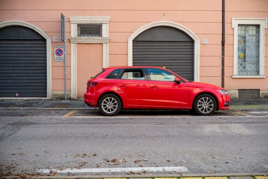 Cremona, Lombardy, Italy October 15th 2024 Audi A3 red car is parked on the side of a residential street in europe, showcasing the typical architecture and street scene