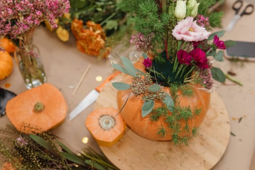 Flower arrangement in a pumpkin, autumn interior decor. Creating handmade autumn decor