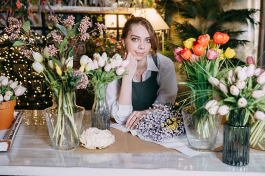 A woman in her florist shop collects bouquets of flowers. The concept of a small business. Bouquets of tulips for the holiday on March 8