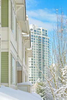 Residential townhouses and high-rise apartment building on bright winter day and cloudy sky background