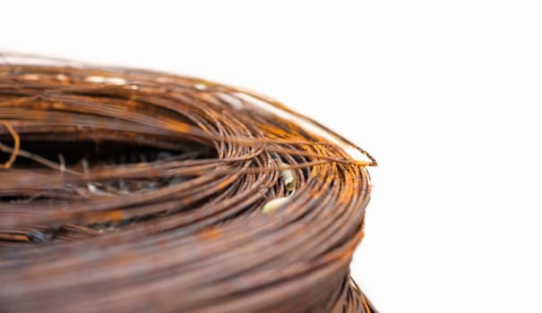 A close-up view of coiled rusted metal wires, highlighting the decay and corrosion. The wires form a circular shape with a smooth light backdrop that contrasts the rugged texture of the rusted material.