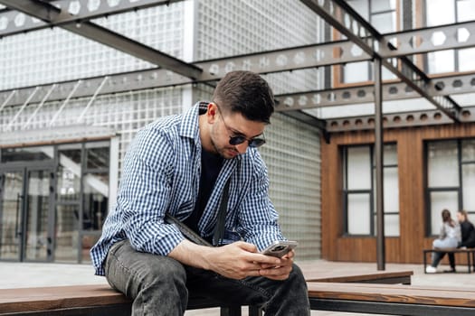 Young man sitting on a bench in a park close up