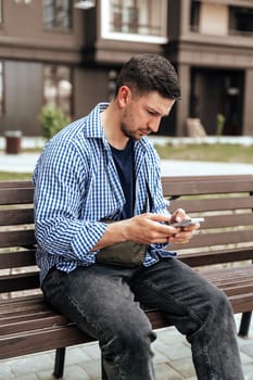 Young man sitting on a bench in a park close up