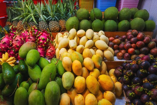 assortment of tropical fruits on market in Asia. Exotic fruits on the counter in a street store in Vietnam. Mango, pitahaya, pineapple, mangosteen and passion fruit