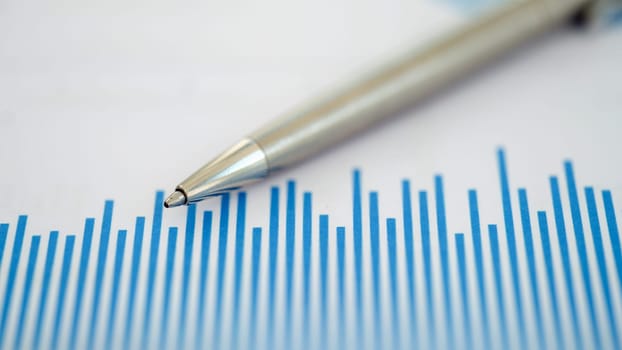 This striking image features a closeup of a pen on a blue chart with important financial data trends