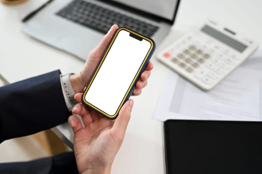 Close up shot of businessman holding mobile phone with white empty display.