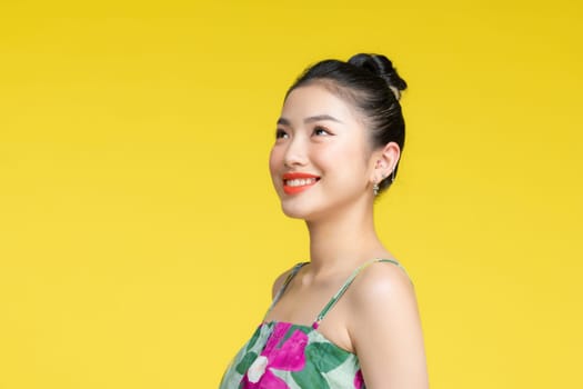 Close up portrait of beautiful asian lady looking away and smiling on yellow background