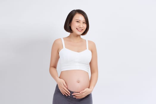 Pregnant woman touching belly on white