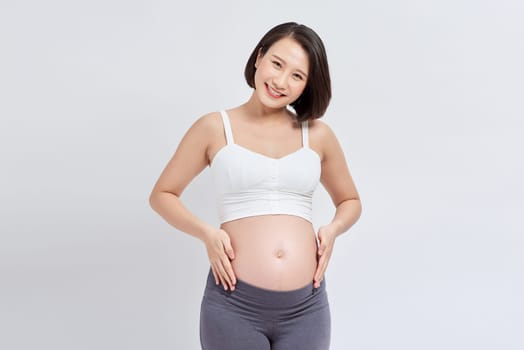 Pregnant woman touching belly on white