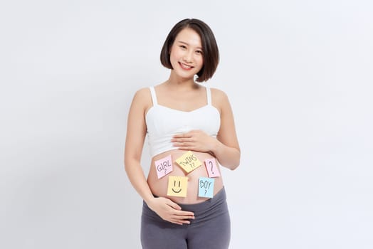 Belly of a young pregnant woman with a white sticker and a question on it (boy or girl concept)