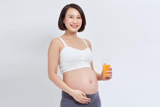 Pretty young pregnant woman with glass of orange juice. isolated on white background