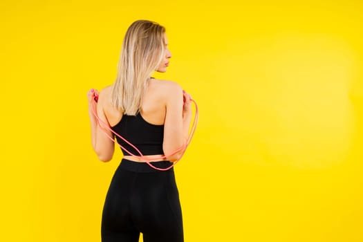 Blond woman with jump rope in a studio, yellow red and dark background