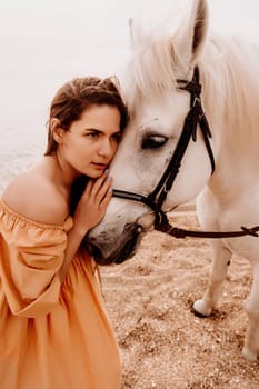 A woman in a dress stands next to a white horse on a beach, with the blue sky and sea in the background