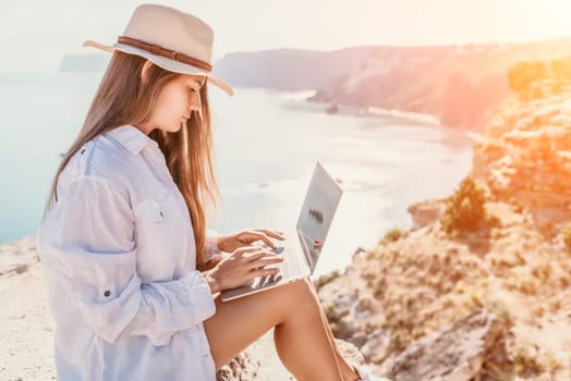 Happy girl doing yoga with laptop working at the beach. beautiful and calm business woman sitting with a laptop in a summer cafe in the lotus position meditating and relaxing. freelance girl remote work beach paradise