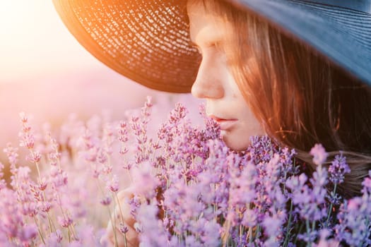 Close up portrait of young beautiful woman in a white dress and a hat is walking in the lavender field and smelling lavender bouquet.