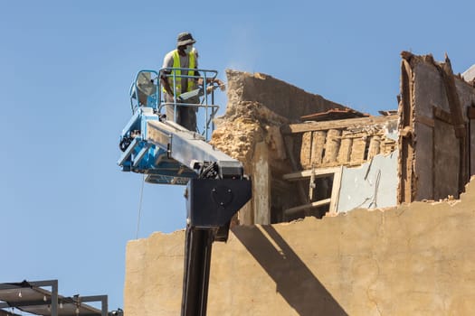 A worker demolish an old stone wall in Europe. Mid shot