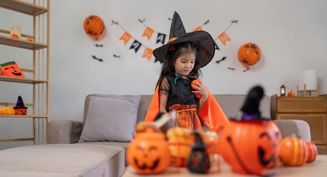 Cute little child girl with pumpkin balloon. Happy family preparing for Halloween.