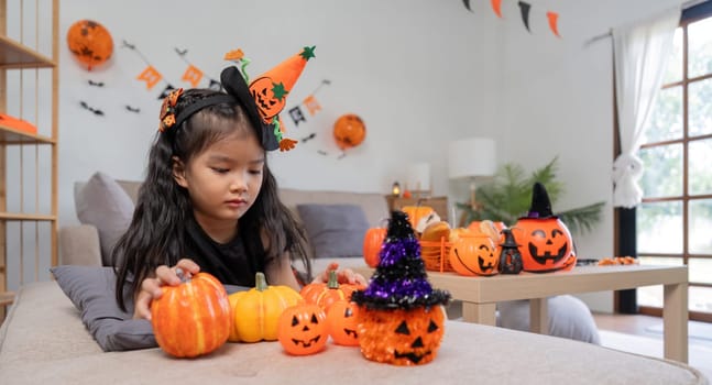 Cute little child girl with pumpkin balloon. Happy family preparing for Halloween.