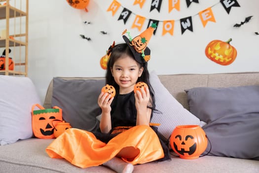 Cute little child girl with pumpkin balloon. Happy family preparing for Halloween.