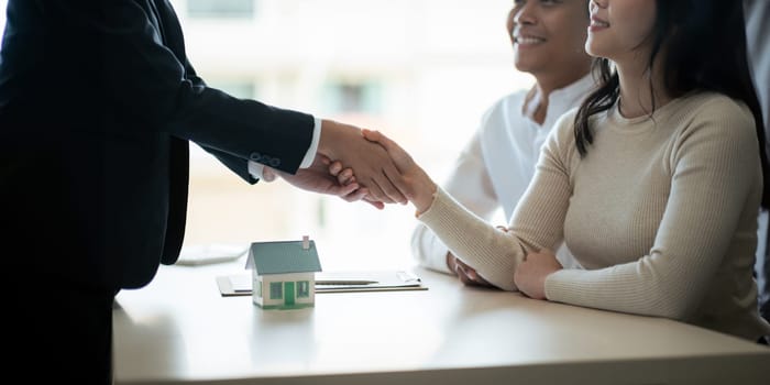 Real estate asian agent shakes hands with husband and wife customer finished contract after about housing insurance and investment loan.