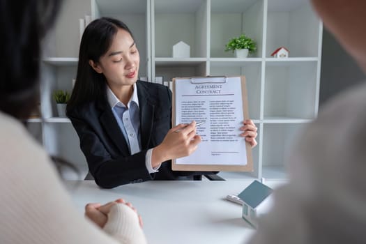 The real estate agent makes an offer to get the couple to sign a contract to buy the house. Happy male and female married customers make intimate deals with agents. real estate concept.