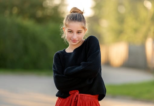 Beautiful teenager girl posing in park outdoors at nature. Pretty teen model in trendy clothes at street portrait