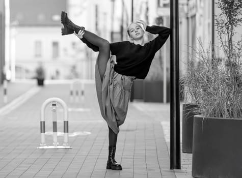 Beautiful teenager girl in red skirt dancing at city street with daylight. Pretty teen model in trendy clothes performing in old town portrait