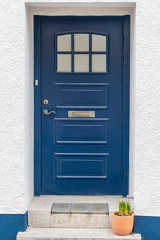 Image of blue wooden entrance door with flowers pot