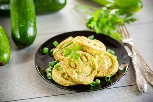 Fried squash green pancakes in a plate, on a wooden table.