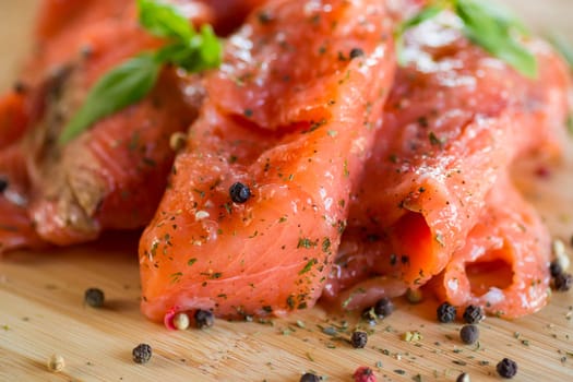 Fresh big pieces of salted red fish with spices and herbs on a wooden board.
