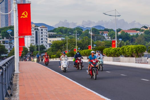 Motorbike transport traffic on the road on a bridge with Vietnam flags in a city in Asia in summer day. Nha Trang, Vietnam - August 22, 2024