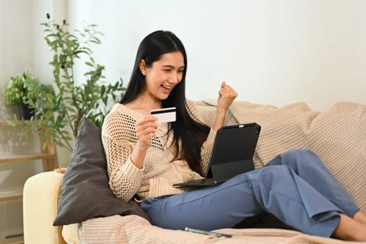Excited woman completing online payment on her digital tablet.
