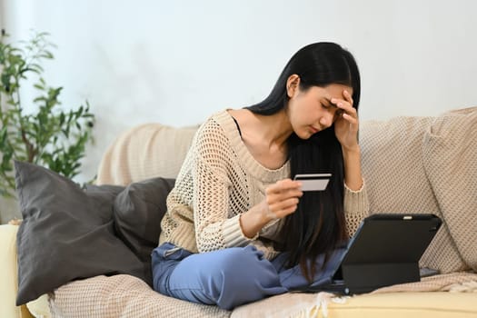 Frustrated woman feeling overwhelmed during online transaction with credit card.