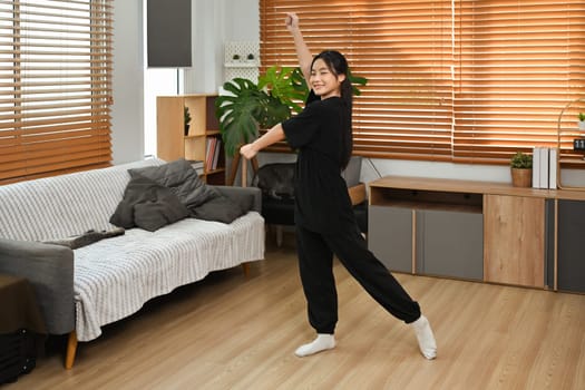 Joyful teenage girl practicing dance moves in her living room.
