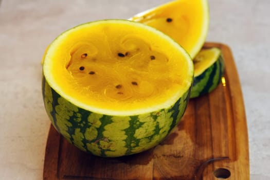 Slices of vibrant yellow watermelon are artistically displayed on a rustic wooden cutting board