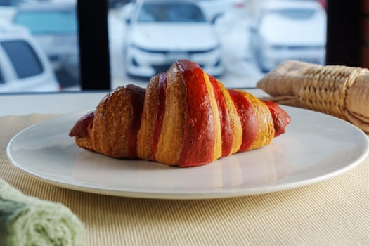 A freshly baked croissant, perfectly golden and flaky, rests on a plate next to a soft linen napkin, creating a warm atmosphere.